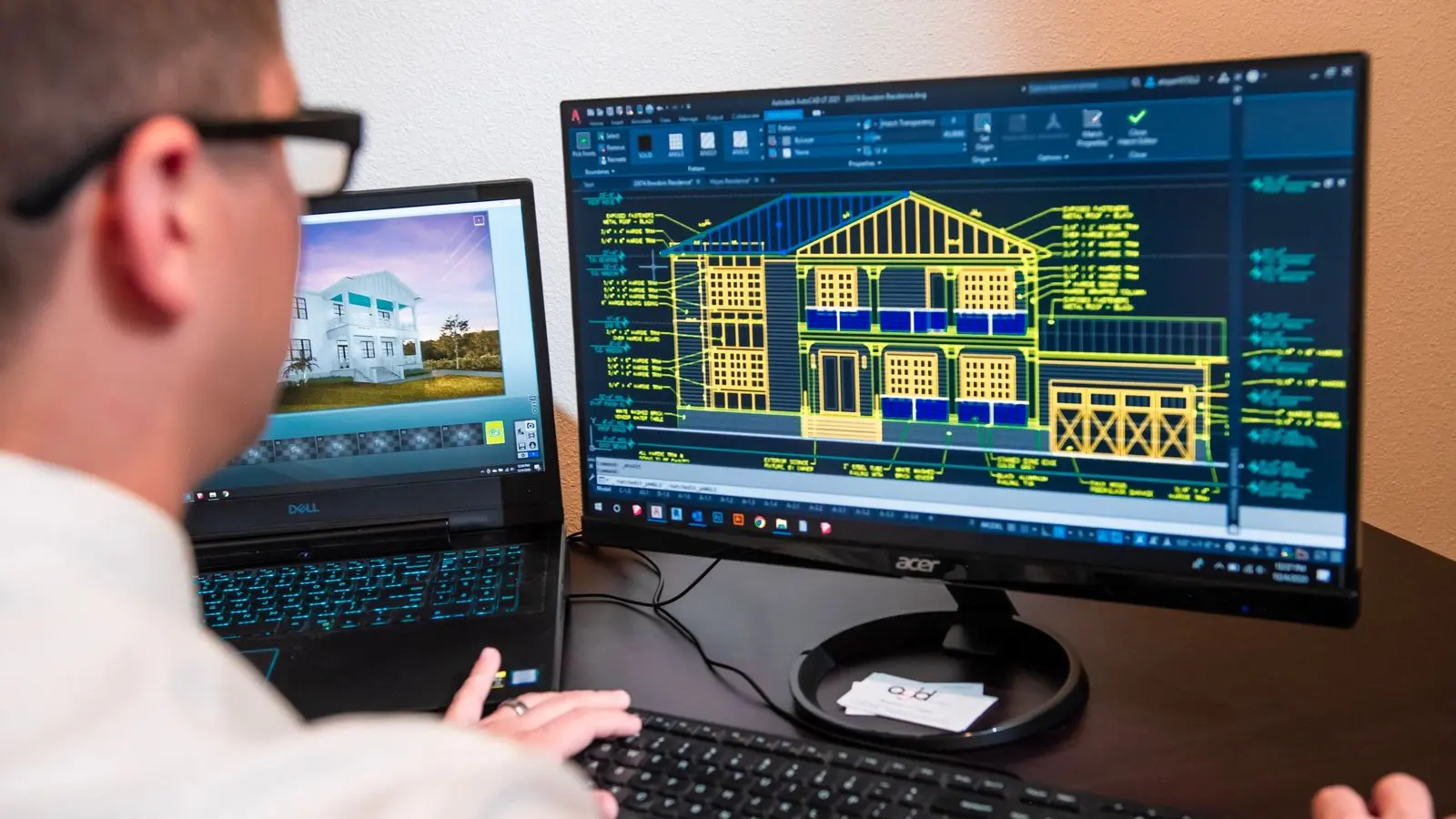 Architect reviewing building drawings and a digital architectural model on two computer screens