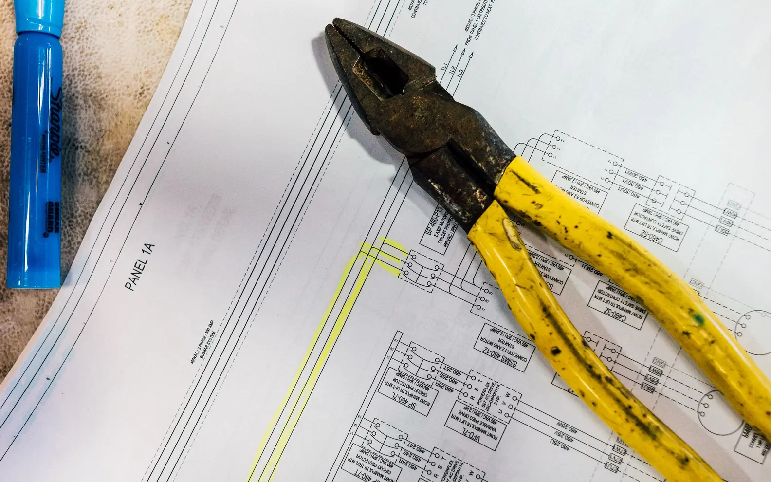 Electrical schematic and hand tools arranged for practical drafting and installation review