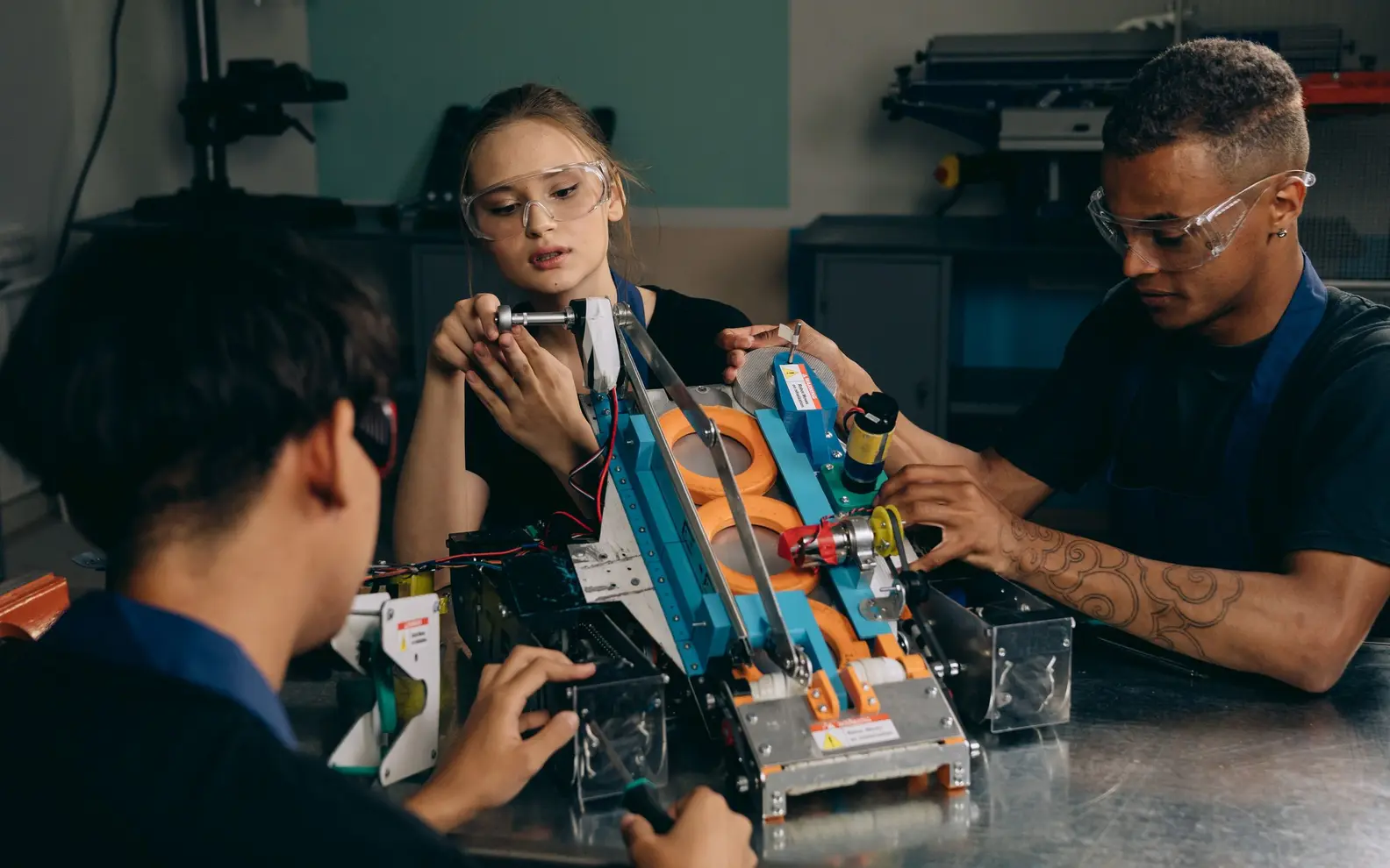Engineering team assembling and reviewing a robotic mechanism in a technical workshop