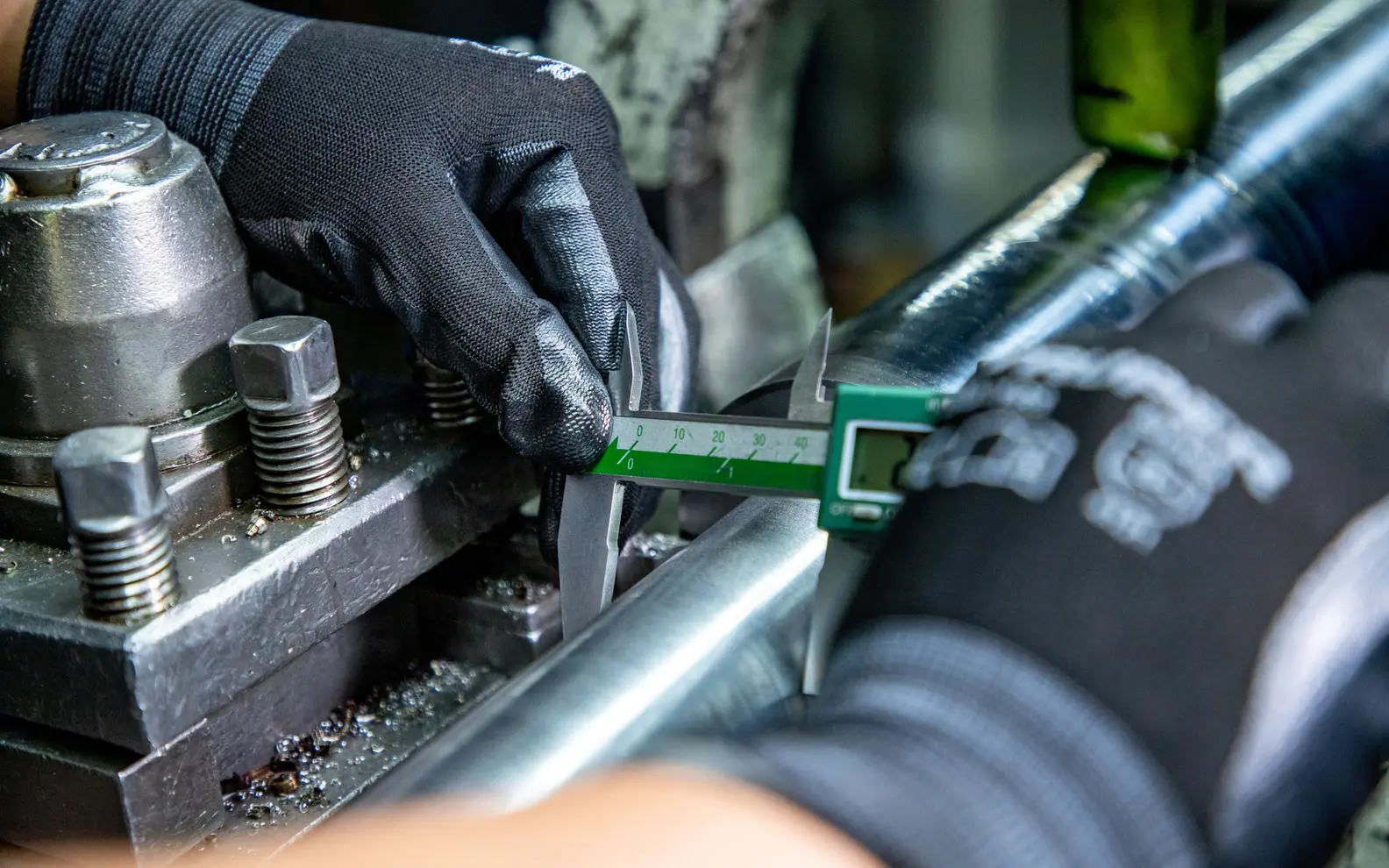 Technician using a digital caliper to inspect a machined metal feature