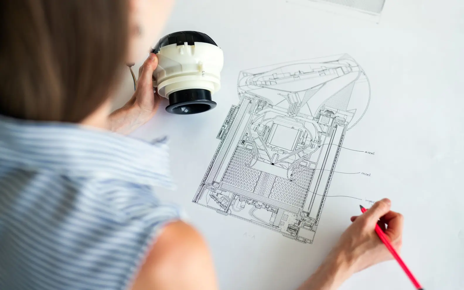 Engineer comparing a physical mechanical component with a detailed legacy technical drawing