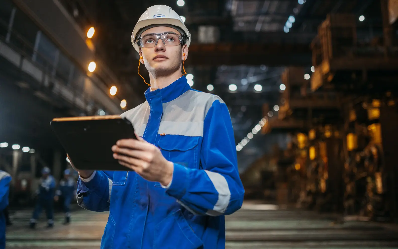 Engineer using a tablet to inspect installed systems and equipment inside a large industrial facility