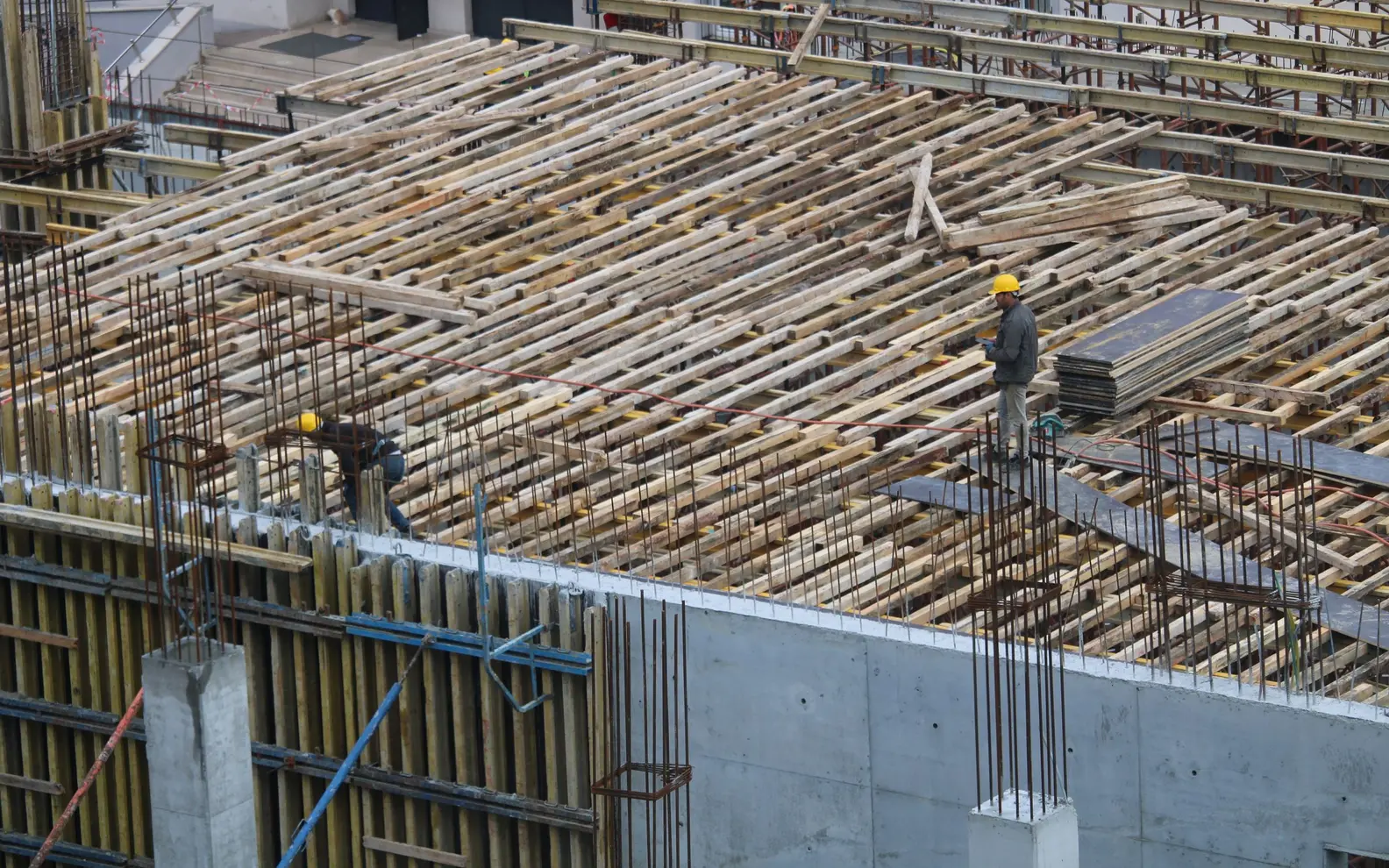 Construction workers installing reinforcement across a reinforced concrete building floor