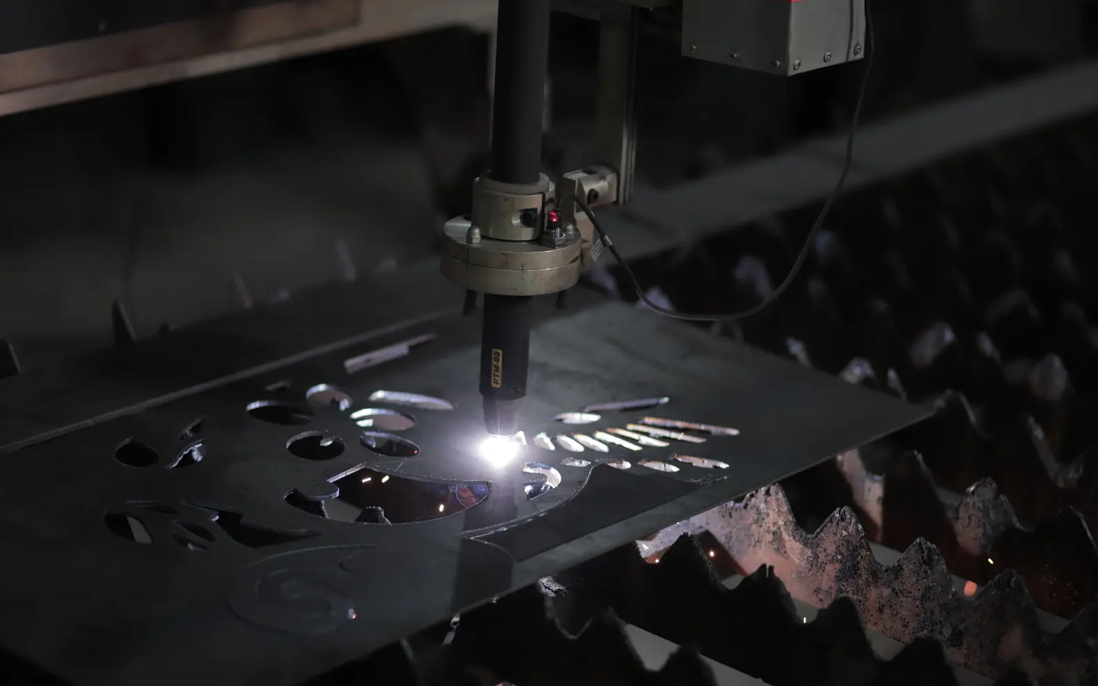 Industrial plasma cutter producing a detailed profile in a flat metal sheet