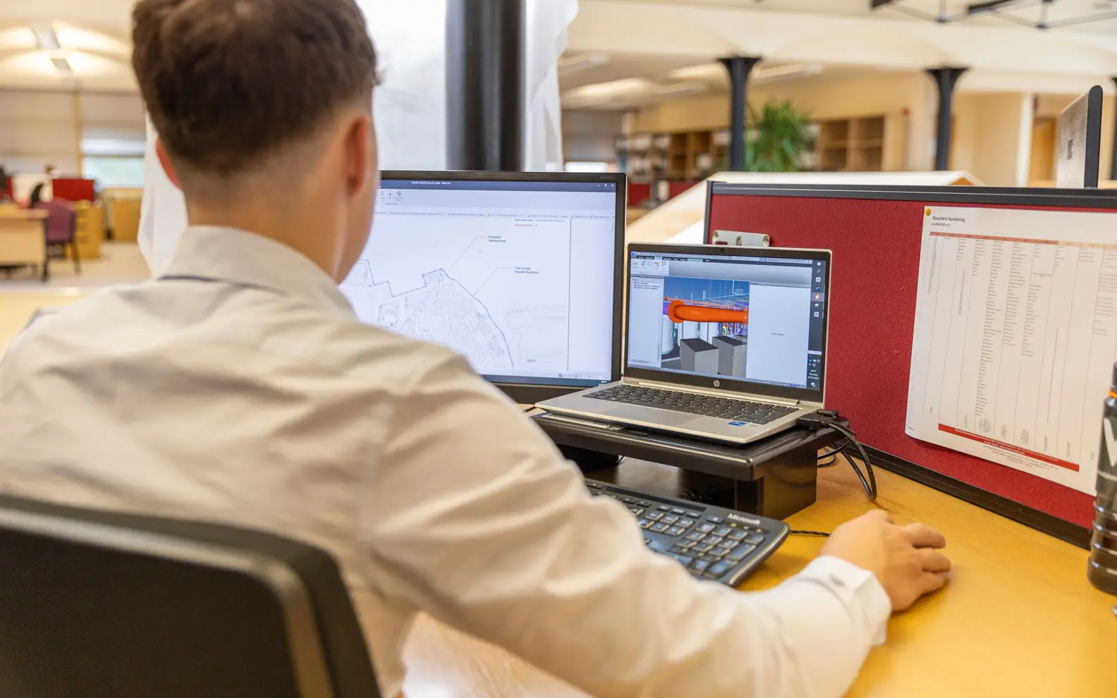 Engineer reviewing a coordinated three-dimensional CAD model at a multi-screen workstation