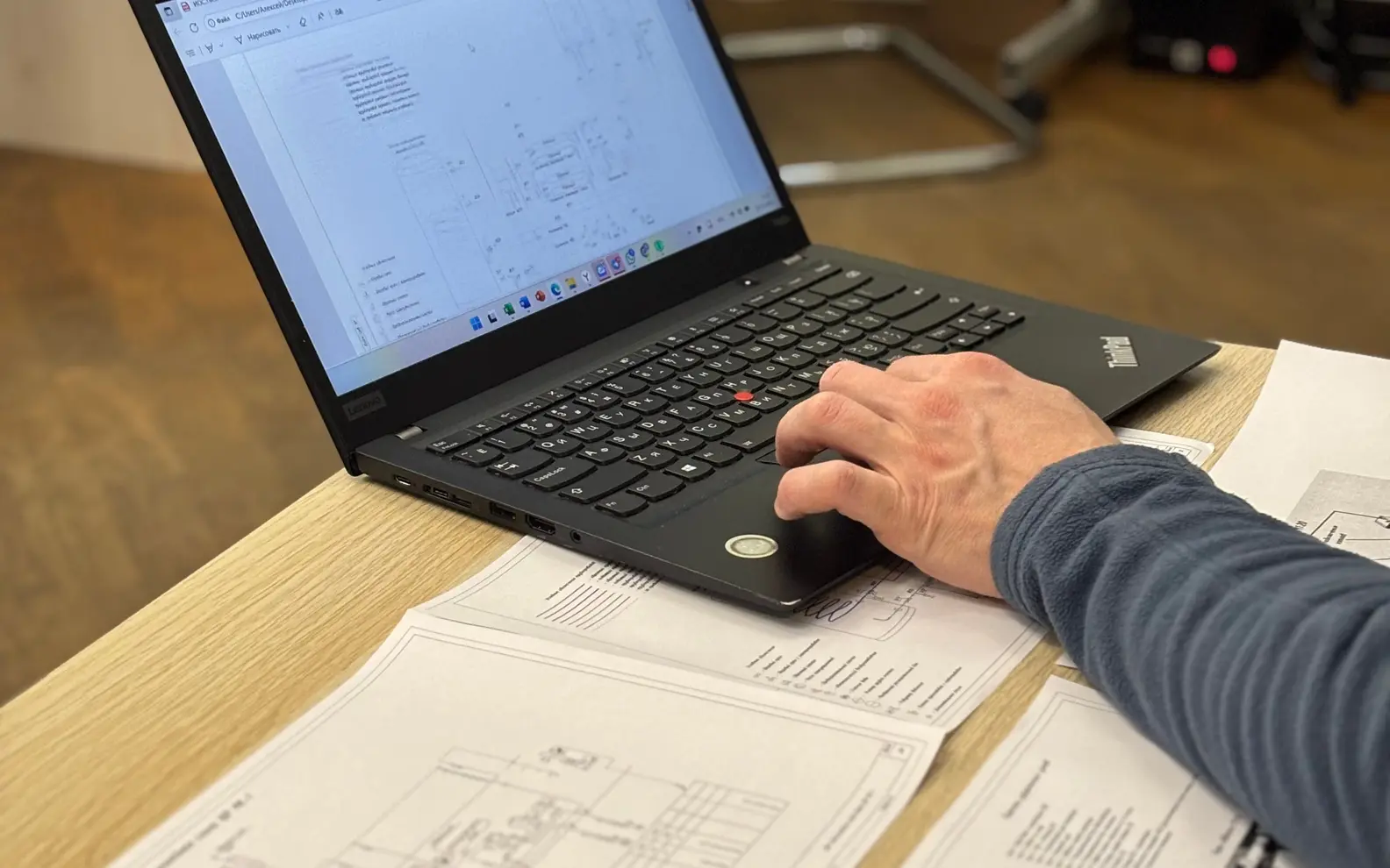 Structural drafter reviewing technical drawings on a laptop above printed engineering sheets
