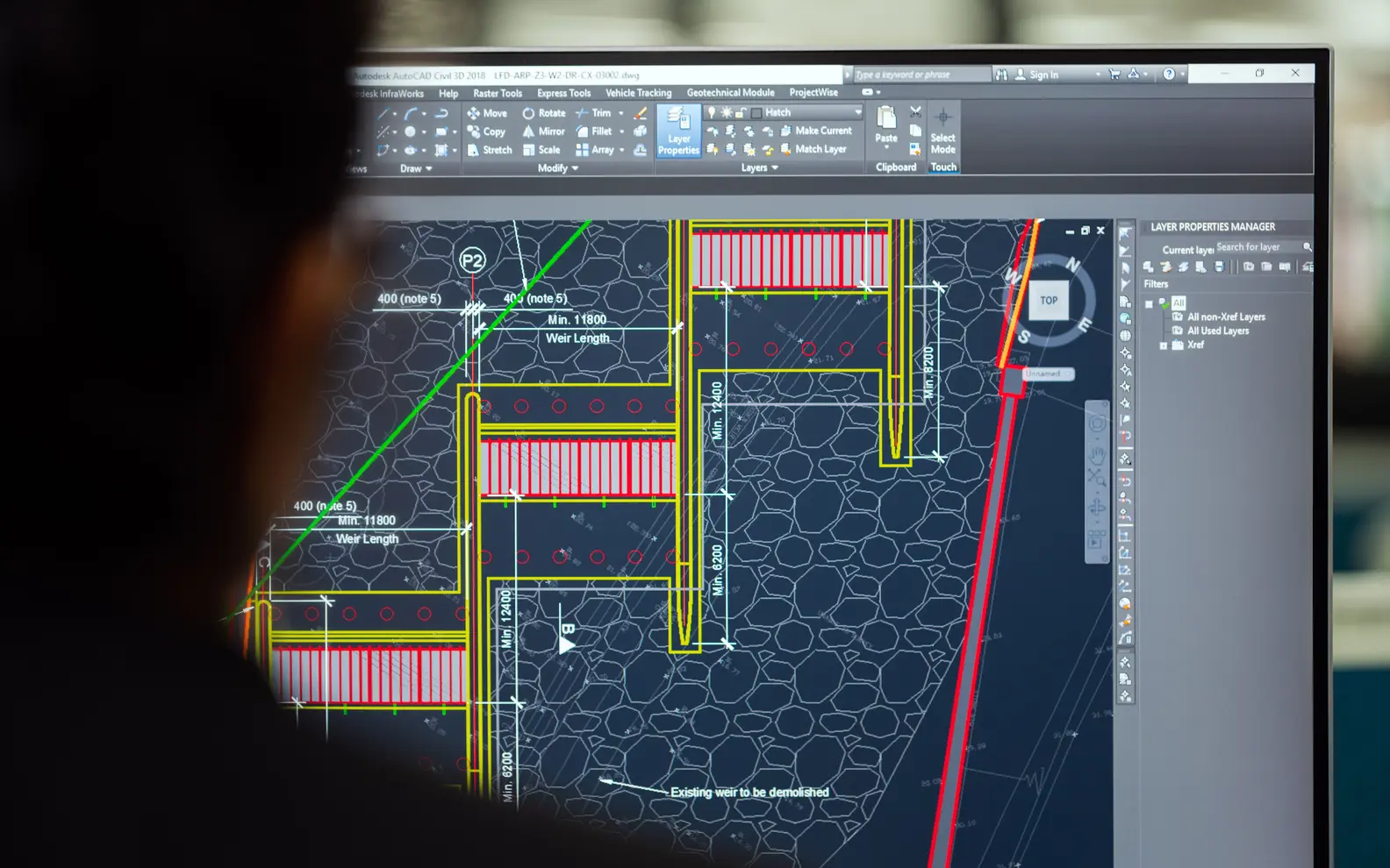 Civil engineer reviewing a detailed digital engineering model on a large office monitor