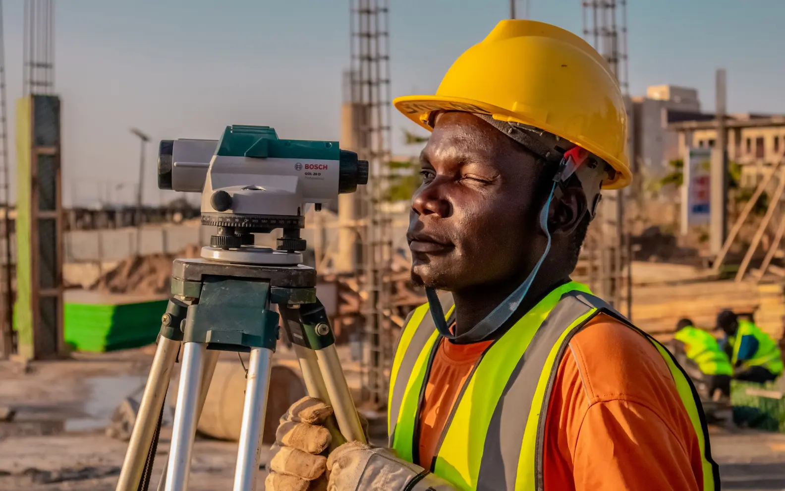 Construction surveyor using precision levelling equipment to verify field conditions on an active building site