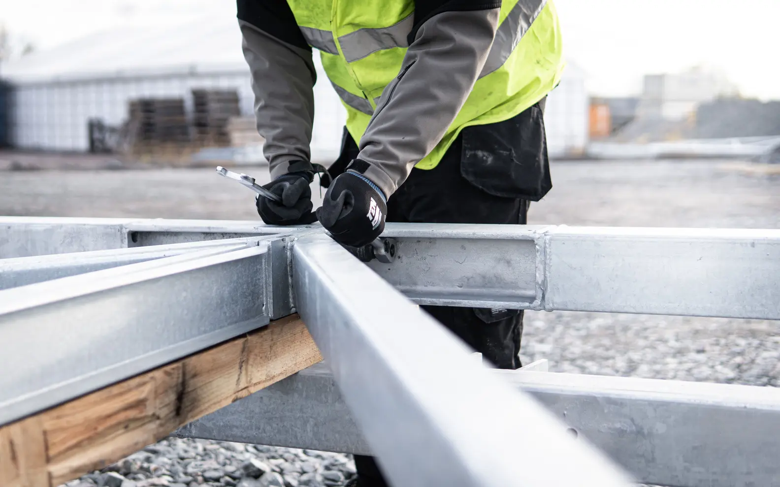 Construction professional aligning and fastening steel framing at a structural connection